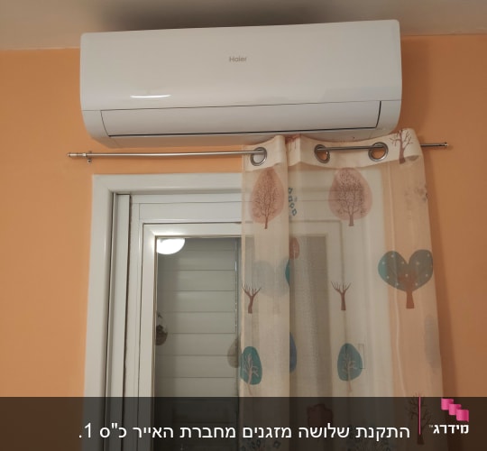מזגן מותקן מעל חלון עם וילון צבעוני